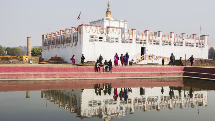 Ein weißer, buddhistischer Tempel spiegelt sich in Wasserbecken