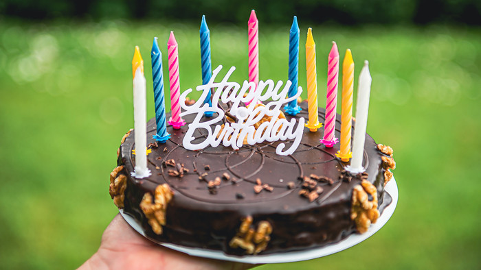 Eine Geburtstagstorte mit bunten Kerzen und einem "Happy Birthday" Schriftzug.