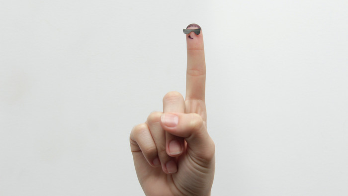 erhobener Zeigefinger mit gebastelter Sonnenbrille, sodass der Finger wie eine Figur aussieht