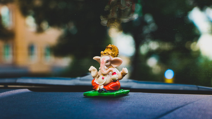 Eine kleine Ganesha-Figur auf einer Autoarmatur.