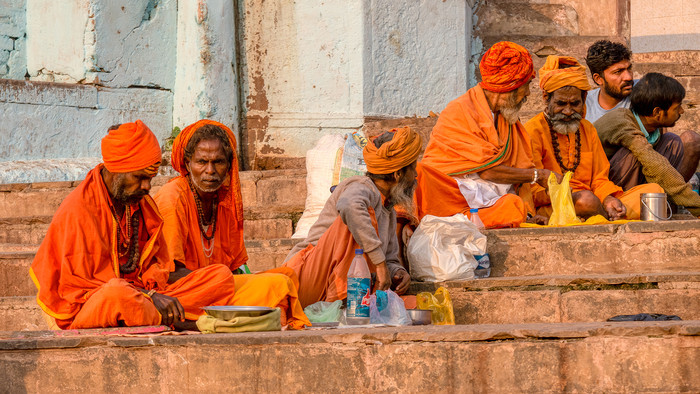 Männer sitzen auf einer Treppe, mehrere von ihnen in orangene Tücher gekleidet