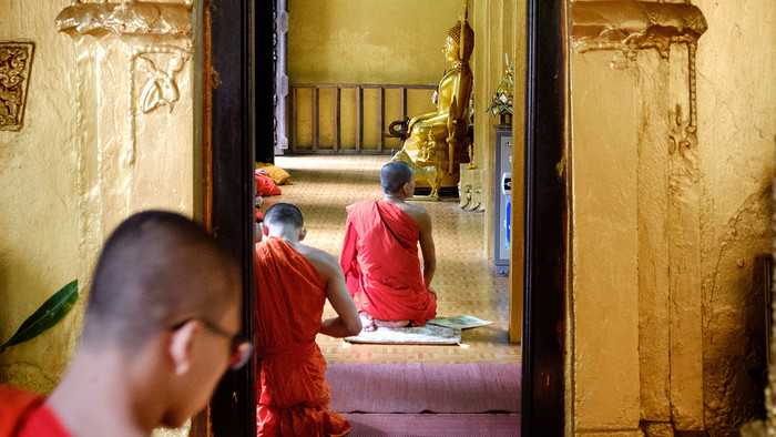 Ein buddhistischer Novize in orangefarbener Kleidung beim Gebet.