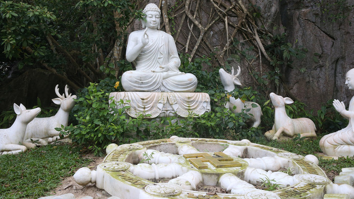 weiße Buddha-Statue mit weißem Dharma-Rad im Vordergrund