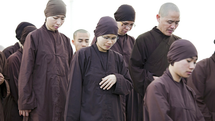 Mönche und Nonnen mit dunkler Kopfbedeckung und dunklen Gewändern mit geneigten Köpfen