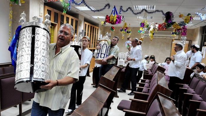 Männer einer jüdischen Gemeinde tragen eine Torarolle herum.