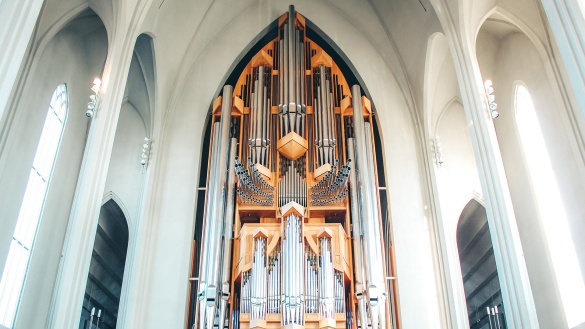 Eine sehr hohe Orgel mit vielen Orgelpfeifen in einer weißen Kirche
