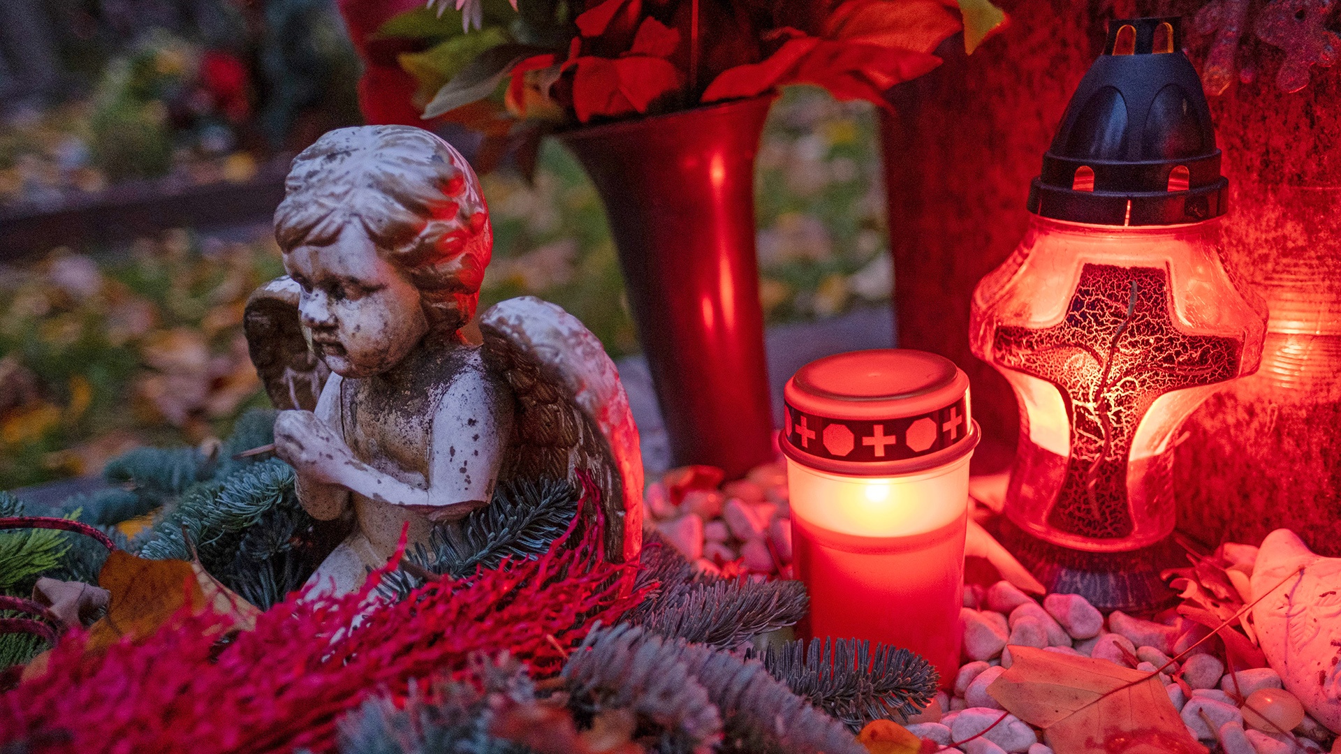 dekoriertes Grab mit einem Engel und brennende Kerzen