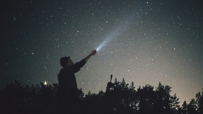 Mann hält Taschenlampe in Nachthimmel