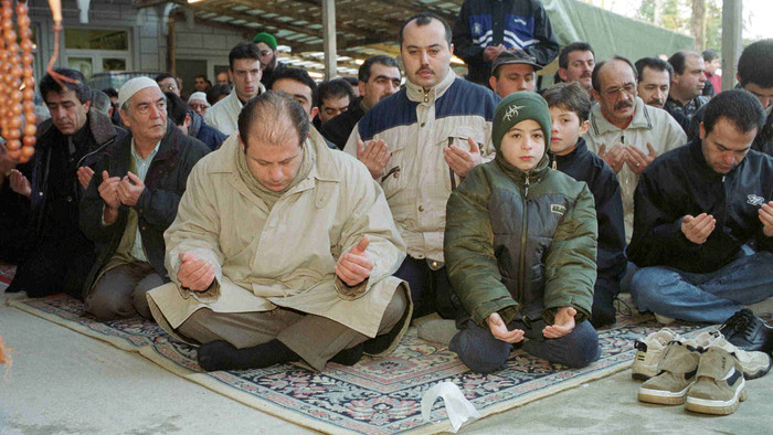 Betende Muslime sitzen im Freien.