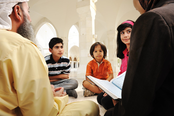 Muslimische Kinder und ein Lehrer mit dem Koran.
