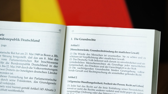 Grundgesetz vor einer Deutschlandfahne, Artikel 1 und 2 sind sichtbar