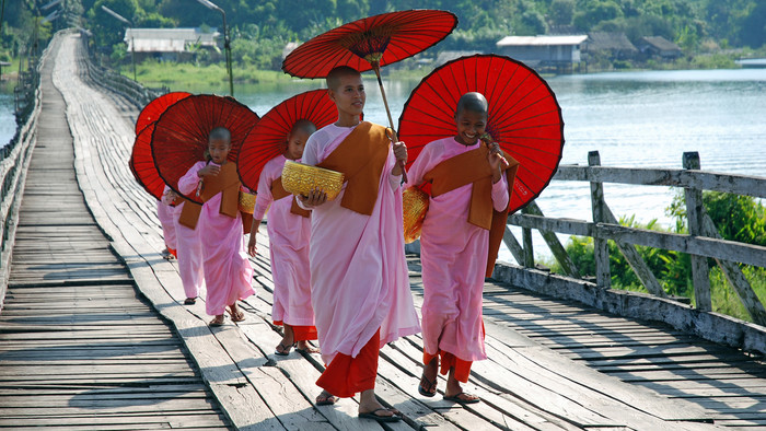 Buddhistische Nonnen in Sanglaburi, Thailand, mit rosa und roten Gewändern und roten Sonnenschirmen