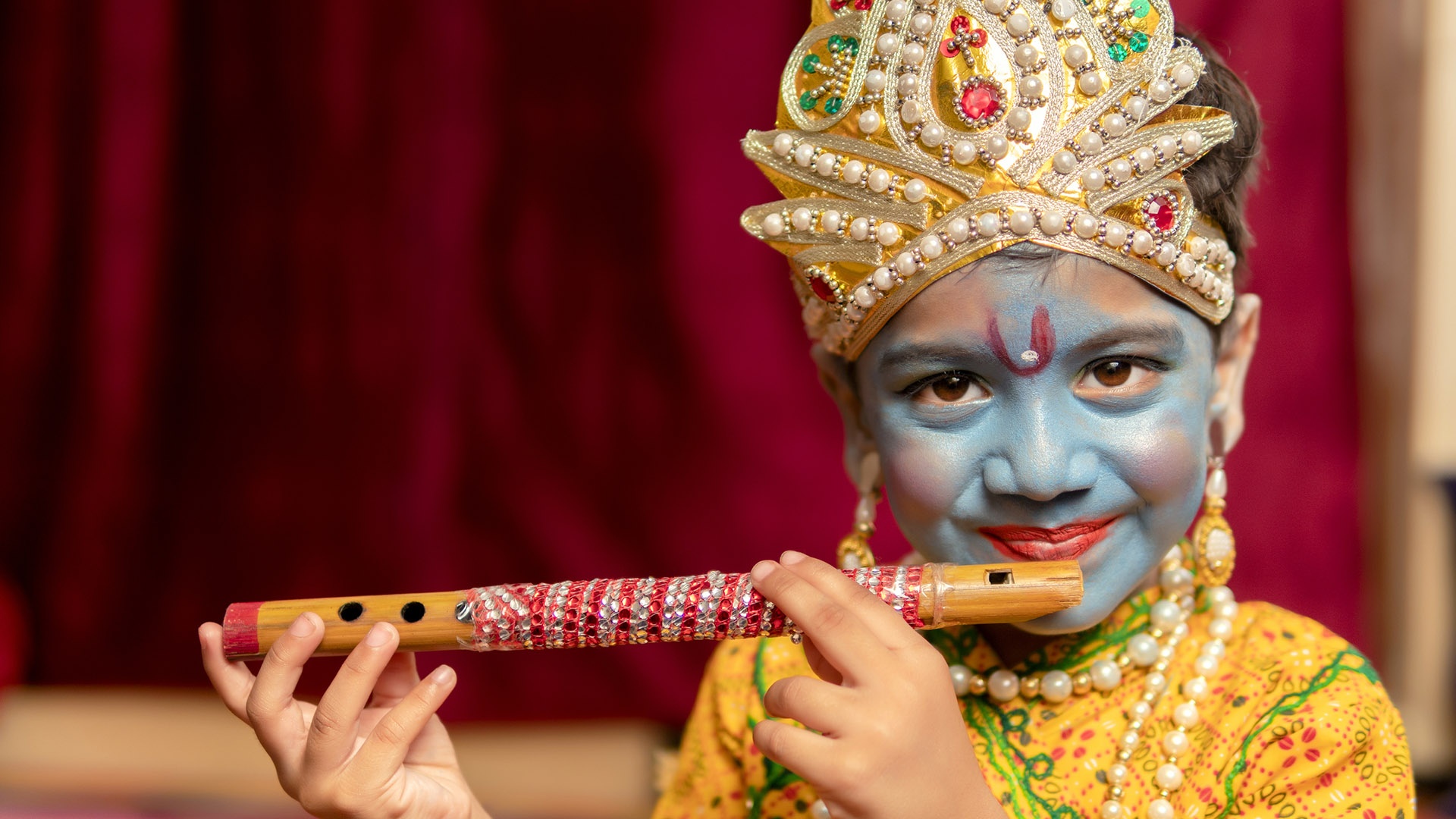 indischer kleiner Junge in Krishna-Kleid mit Flöte