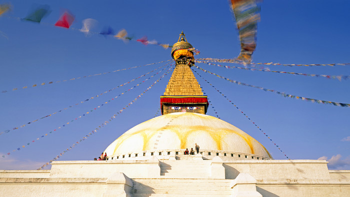 Weiß-gelber buddhistischer Stupa "Bodhnath", Kathmandu in Nepal vor blauem Himmel.
