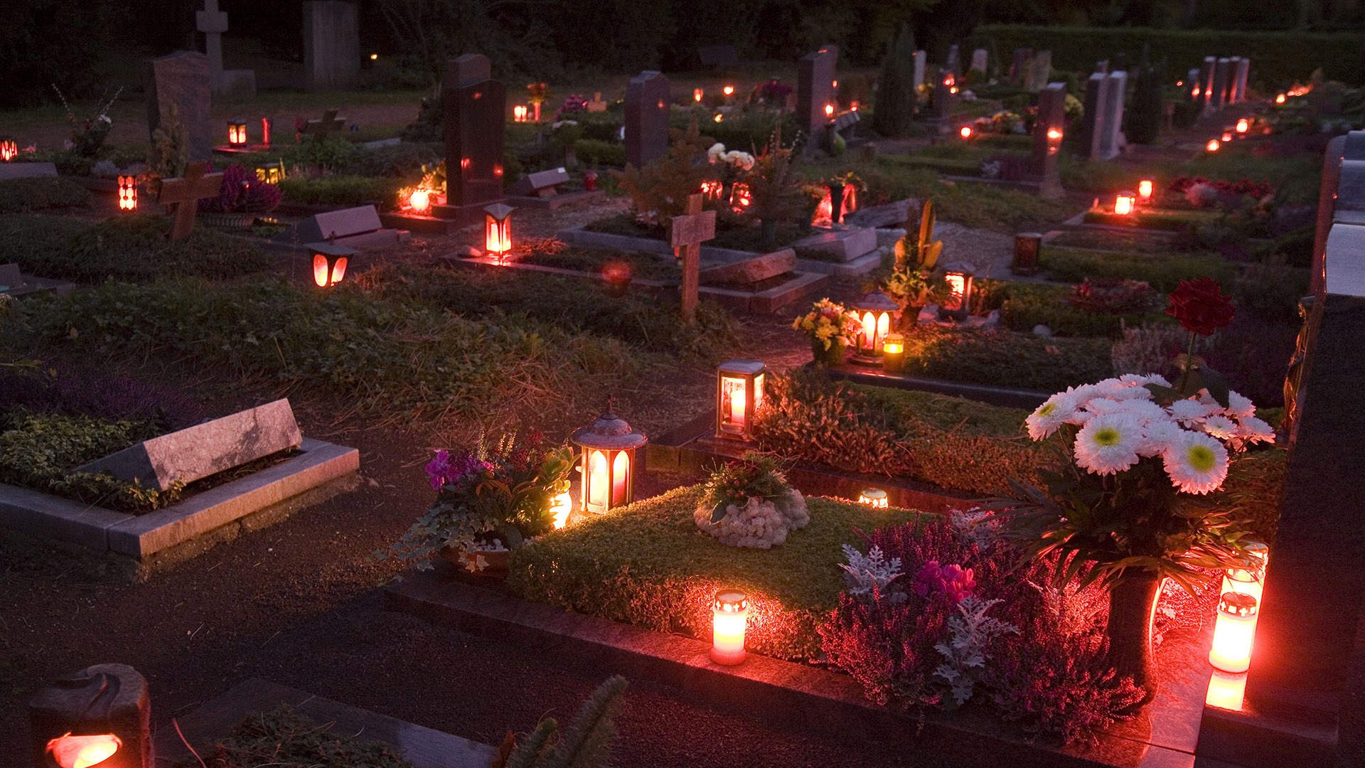mit Kerzen geschmückter Friedhof bei Dunkelheit
