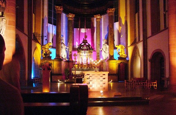 Blick auf den bunt beleuchteten Altarraum der katholischen St. Quintinskirche in Mainz.