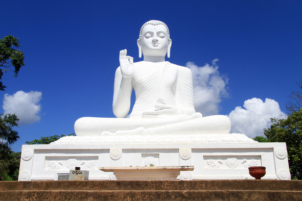 Weißer Buddha vor blauem Himmel.