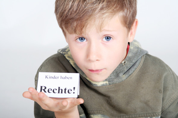 Ein Junge hält ein Schild auf seiner Hand auf dem steht: Kinder haben Rechte!