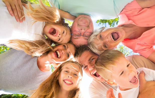 Eine Großfamilie mit Großeltern, Eltern und Kinder lacht zusammen.
