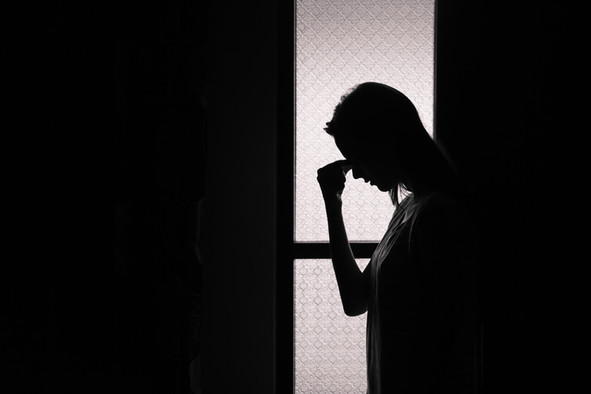 Silhouette einer jungen Frau an einer Glastür.