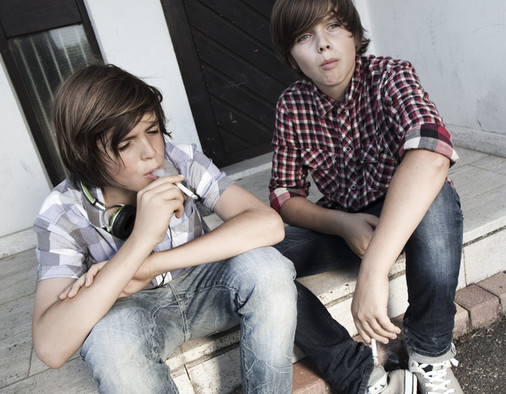 Zwei Jungen sitzen auf einer Treppe und rauchen.