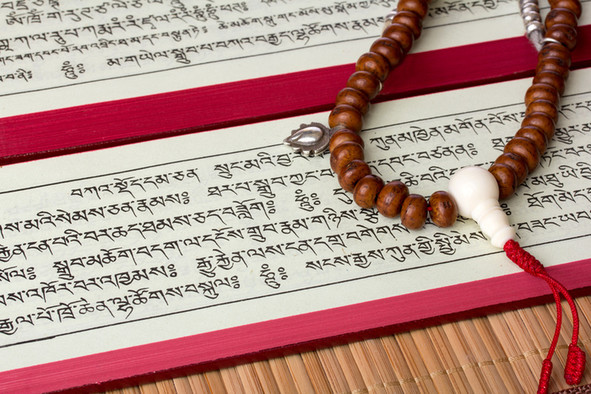 Buddhistischer Text mit Mantrakette aus kleinen braunen Perlen und einer großen weißen Perle.