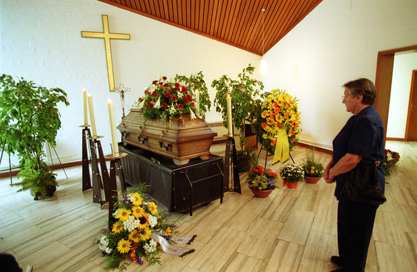 Ein mit Blumengestecken geschmückter Sarg in einer Trauerhalle.