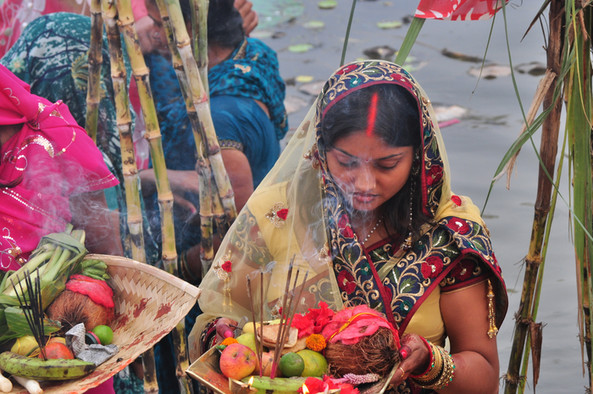 Eine Inderin mit einer Opferschale, gefüllt mit buntem Obst und brennenden Räucherstäbchen.
