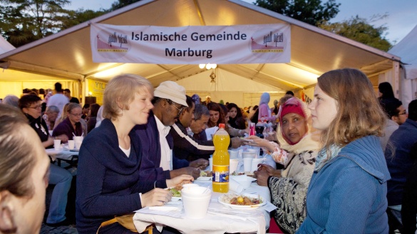 Ramadanzelt in Marburg mit vielen Menschen an langen Tischen.