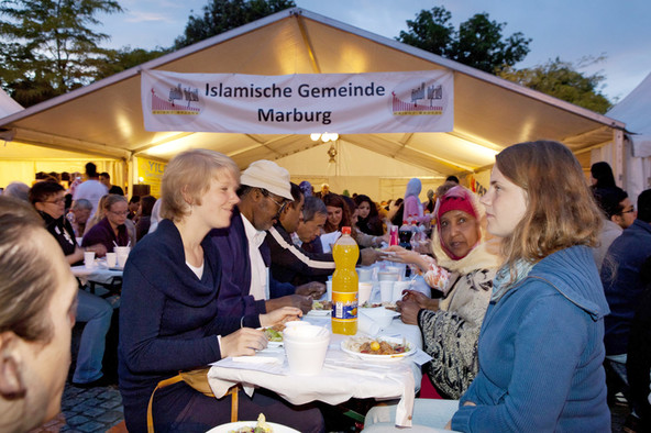 Ramadanzelt in Marburg mit vielen Menschen an langen Tischen.