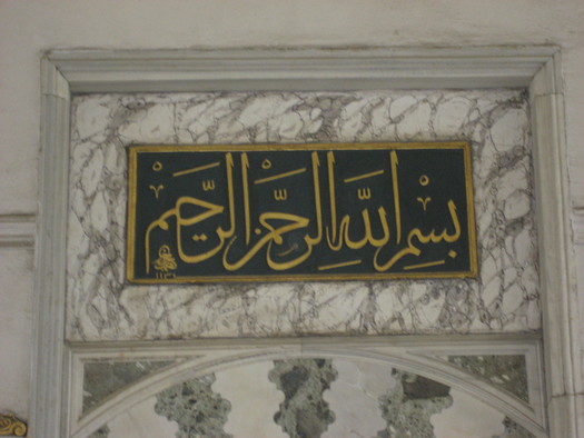 Der muslimische Segensspruch Basmallah in arabischer Schrift an einer Wand in einer Moschee.