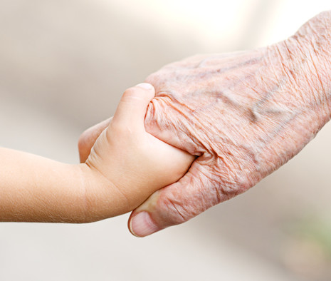 Eine Kinderhand hält die Hand eines alten Menschen. 