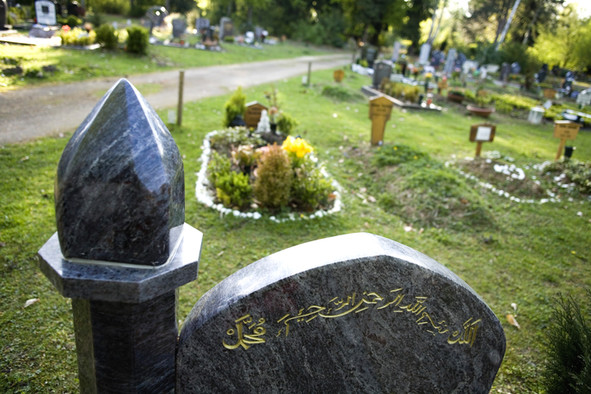 Dunkelgraue Grabsteine mit arabischen Schriftzeichen auf einem deutschen Friedhof.