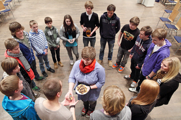 Jugendliche feiern das Abendmahl in einem Kreis mit Brot.