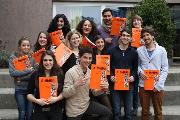 Eine Gruppe von Mädchen und Jungen, die alle ein orangefarbenes Buch in den Händen halten.