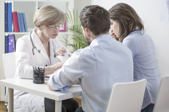 Ein junges Paar im Beratungsgespräch mit einer Ärztin.