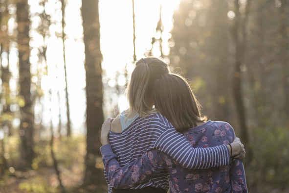 Zwei junge Frauen Arm in Arm im Wald.