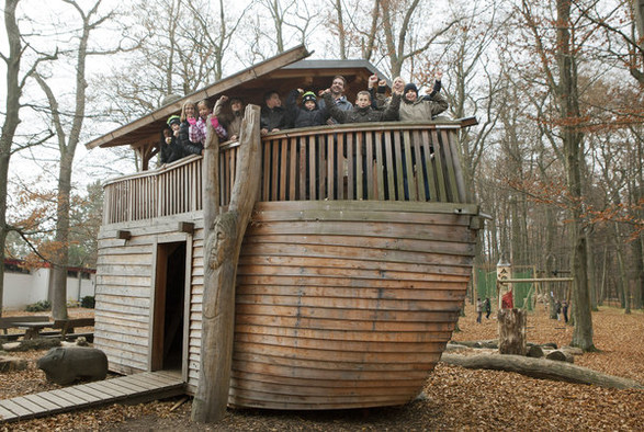 Ein kleinerer Nachbau einer Arche Noah aus Holz im Bibelpark Vogelsberg mit winkenden Kindern an Bord.