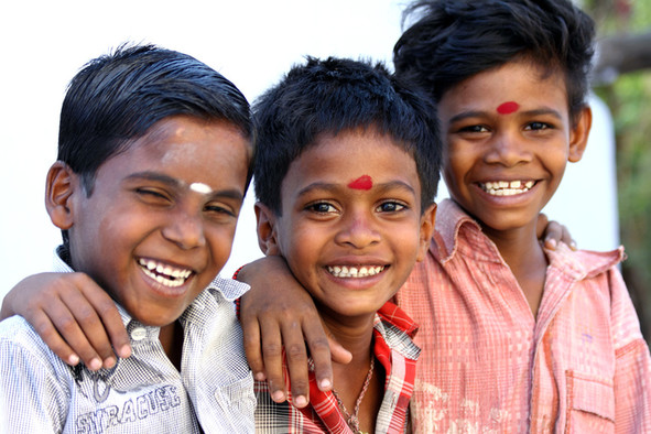 Drei lachende Jungen mit einem weißem oder einem roten Punkt auf der Stirn.