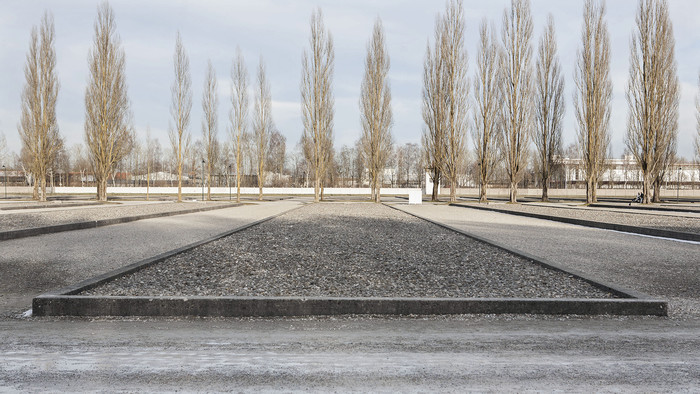 Gedenkstätte KZ Dachau: graues Steinfeld mit Bäumen im Hintergrund