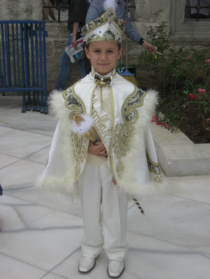 Ein Junge in weißer Kleidung und mit weißem Hut beim islamischen Beschneidungsfest.