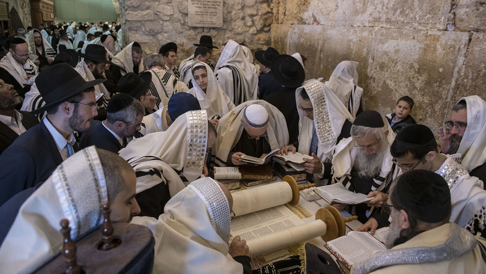 Männer und Jungen in hellen Schals und schwarzen Hüten an der Klagemauer lesen in Büchern und der Tora