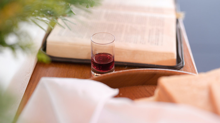 Unscharfer Blick auf eine aufgeschlagene Bibel und ein Glas Wein oder Traubensaft