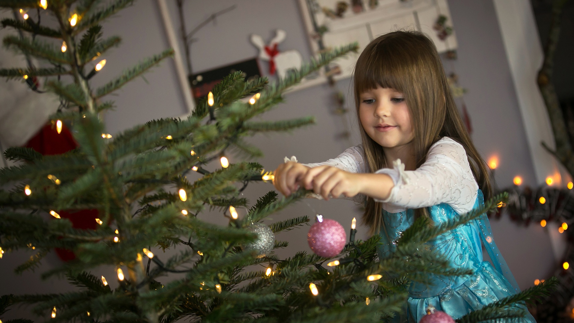 Mädchen schmückt Tannenbaum zu Weihnachten