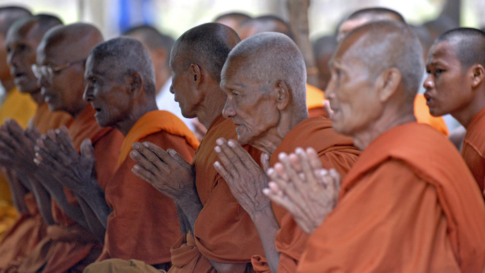 buddhistische Mönche in orangefarbener Kleidung beim Meditieren
