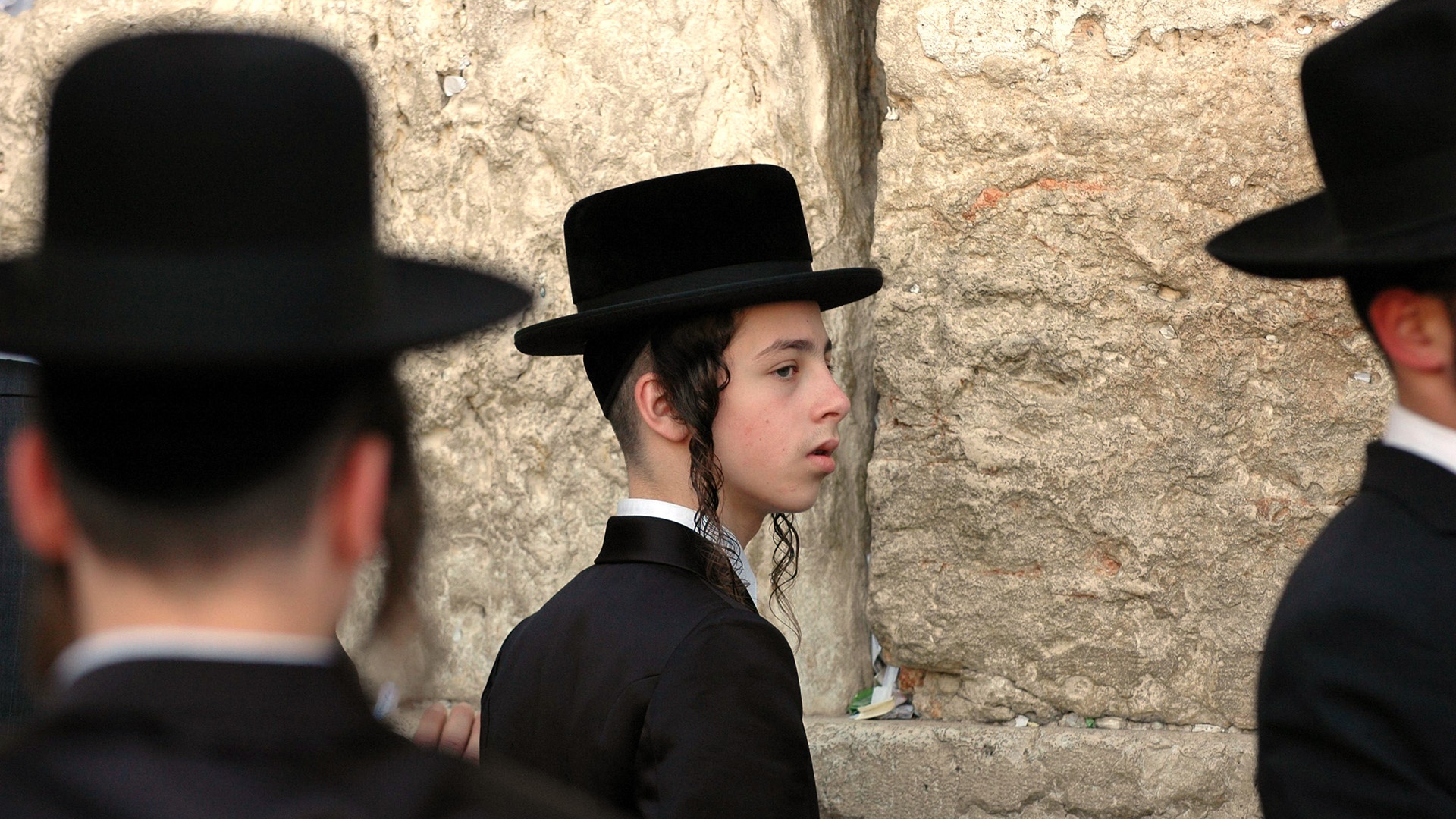 Jüdischer Junge mit Schläfenlocken und traditionellem Hut an der Klagemauer