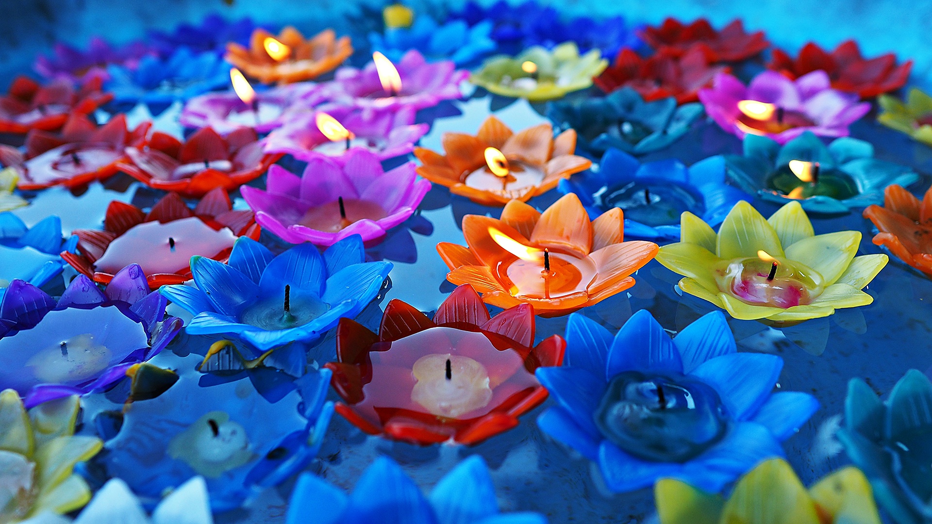 Mehrfarbige, auf dem Wasser schwimmende Lotuskerzen in Thailand.