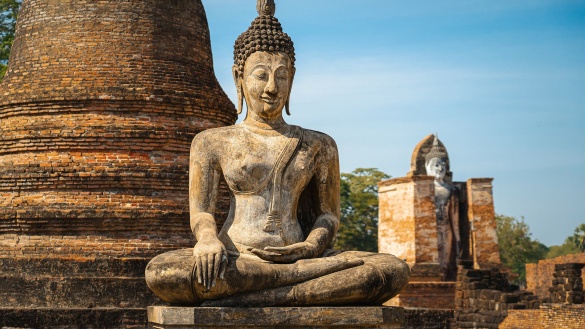 Buddha-Statue in Thailand vor blauem Himmel.