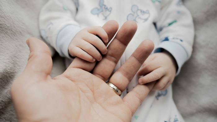 Baby hält Hand einer erwachsenen Person