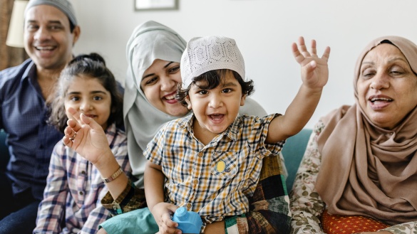 Eine muslimische Familie lacht und winkt.